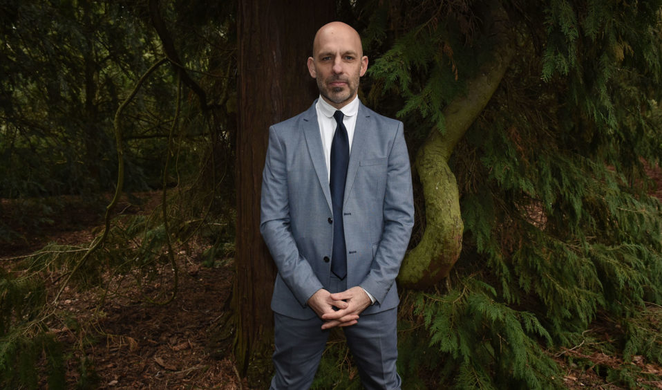 Man standing with hands clasped in woods